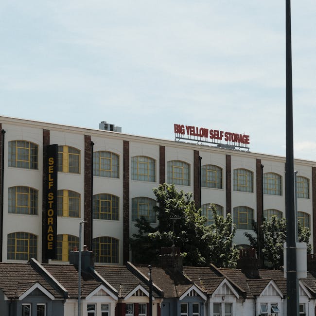 A street scene showing the exterior of a large, historic multi-storey building with white and red brickwork, located on Bedford Hill in Balham. In the foreground, a sidewalk with tactile paving and a
